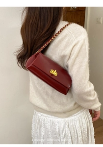 Detail of burgundy leather shoulder bag with gold twist lock and woven chain strap
