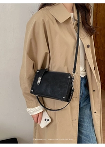 Minimalist black baguette bag with silver rivets shown as a shoulder bag on a model