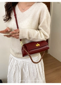 Detail of burgundy glossy leather bag with gold twist lock and red-gold chain strap