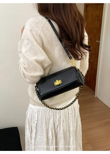 Detail of black glossy leather shoulder bag with gold metal twist lock and dual straps