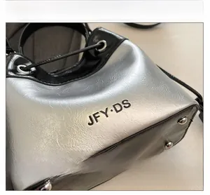 Detail of silver textured bucket bag with JFY DS logo and metal grommet drawstring