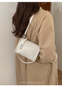 Close-up of cream white baguette bag with pleated leather texture and silver buckle detail