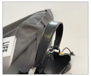 Detail of black bucket bag handle featuring precise stitching and silver metal hardware