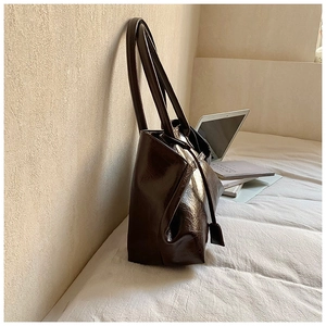 Detail view of large coffee brown oil-wax leather tote bag in professional work setting