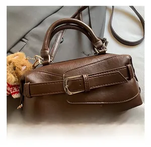 Dettaglio borsa a bauletto marrone vintage con fibbia in metallo e ciondolo a orsetto