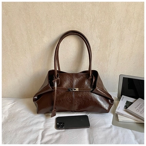 Detail of dark brown oil wax leather tote bag featuring a silver metal buckle closure
