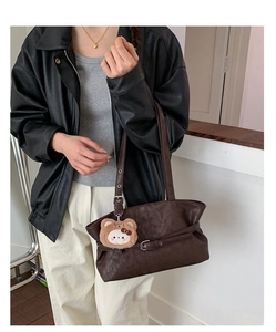 Detail of dark brown tote bag with metal buckle strap and plush bear charm on strap