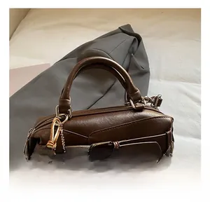 Dettaglio della borsa Boston vintage marrone scuro con fibbia e ciondolo a orsetto