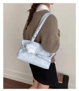 Detail of blue leather tote bag with buckle strap and star plush charm on model