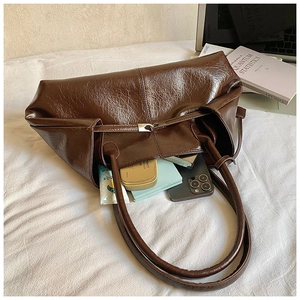 Detail of a brown oil-wax leather tote bag showing large capacity and adjustable straps