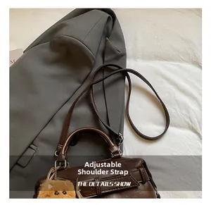 Dettaglio borsa vintage in pelle caffè con tracolla regolabile e ciondolo a peluche