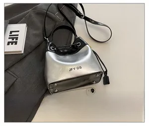 Detail showing the silver metallic bucket bag with black trim and metal feet on the bottom