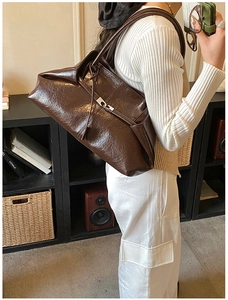 Detail of a large dark brown oily leather tote bag shown on a model for daily commute