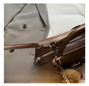Dettaglio borsa in pelle marrone con gancio in argento e ciondolo di peluche