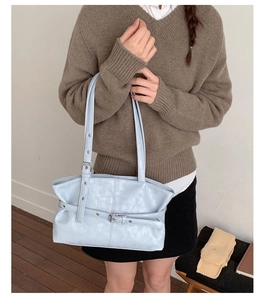 Light blue faux leather tote bag with decorative buckle shown on a shoulder