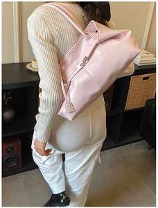 Detail of pink textured leather tote bag with silver buckle worn by a model in lifestyle setting
