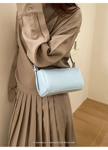 Close-up of light blue bolster bag with lychee grain texture worn by a model