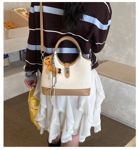 Detail of a contrast color tote bag with horse charm and metal buckle closure
