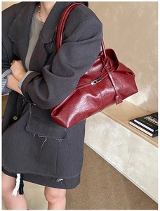 Detail of burgundy glossy oil wax leather tote featuring silver buckle and side straps