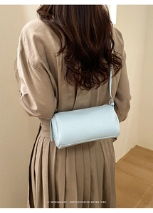 Close-up of light blue lychee pattern cylindrical crossbody bag on khaki dress