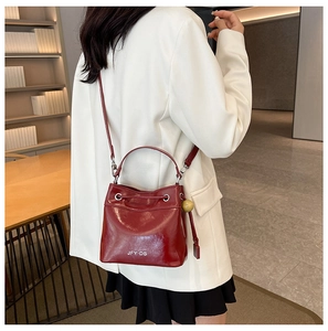 Detail of red bucket bag with polished leather texture and round wood bead charm