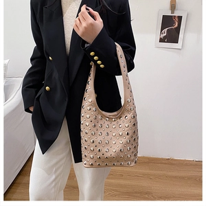 Détail du sac hobo en cuir beige avec des rivets argentés et une large bandoulière