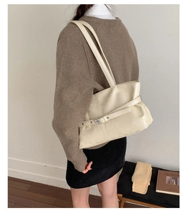 Close-up of minimalist beige leather tote bag featuring side belt buckle decoration