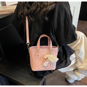 Seitenansicht einer rosa glänzenden Beuteltasche mit Herzanhänger und Spitzenschleife