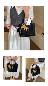 Detail of black leather tote bag with elegant gold clasp and horse-shaped charm