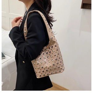 Detail of beige rivet hobo bag with silver studs worn with a black blazer