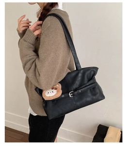 Detail of black vintage shoulder bag with silver buckle and cute plush cat pendant