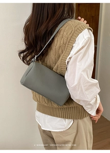 Detail of grey cylinder bag showing premium pebbled leather texture on model