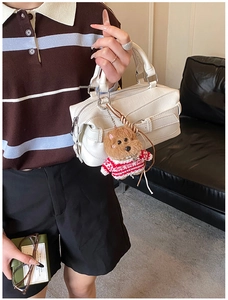 Dettaglio della borsa a mano beige vintage con ciondolo a forma di cucciolo di peluche