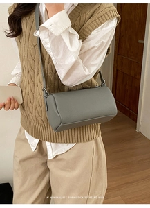 Detail of grey lychee leather cylinder bag showing texture and slim shoulder strap