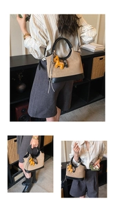 Detail of khaki bucket bag with black trim and yellow horse charm shown by model