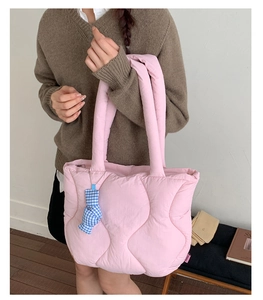Detail of pink quilted puffer shoulder bag with wave stitching and blue plaid charm