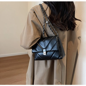 Détail du sac en cuir noir matelassé en V avec chaîne argentée et fermoir rotatif