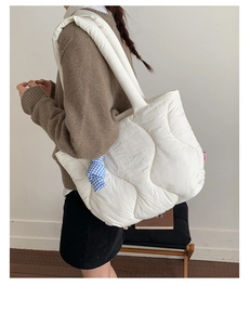 Detailed view of white quilted shoulder bag with blue plaid charm and fashion label