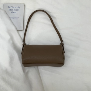 Flat lay of a brown litchi pattern leather baguette bag with metal buckle detail