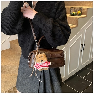 Dettaglio borsa a mano marrone scuro vintage in ecopelle con fibbia e ciondolo peluche