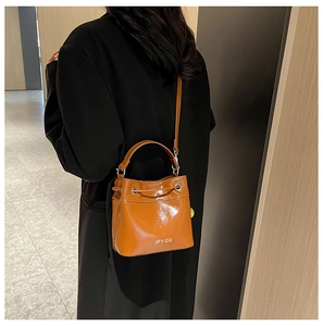 Detail of an orange bucket bag with adjustable strap and brand logo in a luxury setting
