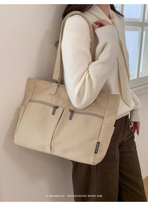 Λεπτομέρεια μεγάλης κρεμ υφασμάτινης τσάντας tote με λειτουργικές τσέπες με φερμουάρ