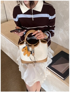 Detail of off-white tote bag with brown trim, silver lock and leather horse charm