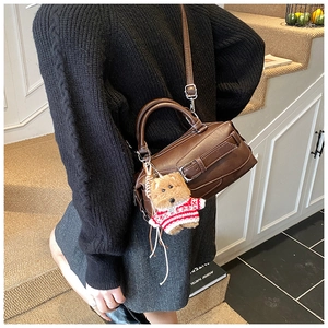 Dettaglio della borsa boston in pelle marrone scuro con ciondolo a orso e tracolla