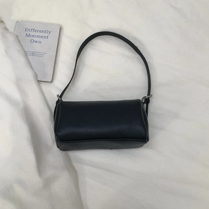 Detailed top-down view of black pebble leather pillow bag on white fabric background