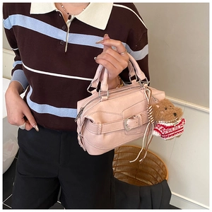 Dettaglio della borsa Boston in pelle rosa con fibbia decorativa e ciondolo a orsetto