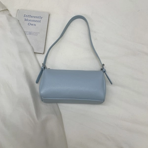 Detail of light blue litchi grain leather texture and adjustable strap buckle on bag