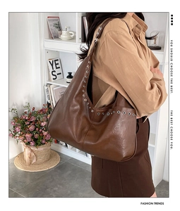 Detail of a large brown leather Hobo tote bag with stylish metallic eyelet decorations
