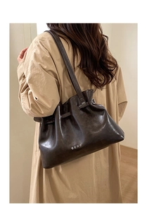 Side view of a vintage dark brown pleated leather tote bag worn with an autumn coat