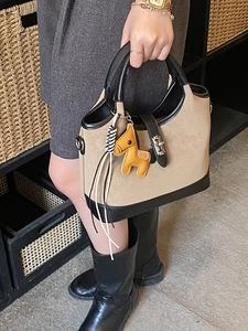Chic beige leather tote bag with black contrast trim and a yellow horse charm detail